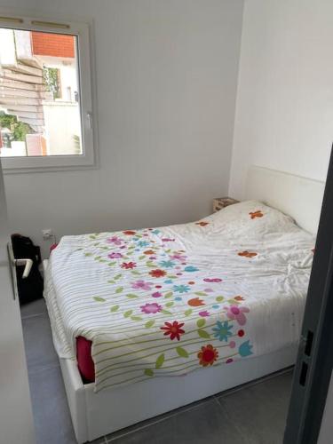 - un lit blanc orné de fleurs dans la chambre dans l'établissement Résidence Tahiti Beach Appart bord de mer, piscine à frontignan plage, à Frontignan