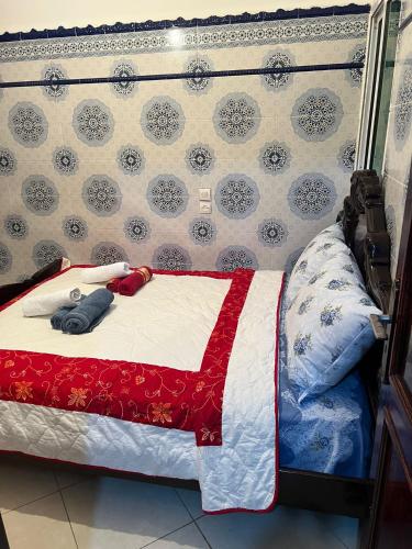 ein Bett mit einer roten und weißen Bettdecke darauf in der Unterkunft شقة مفروشة مجهزة قريبة من مطار سايس in Fès