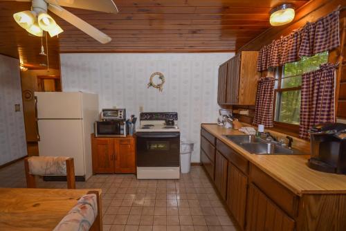 a kitchen with a stove and a sink and a refrigerator at The Pines in Swanton