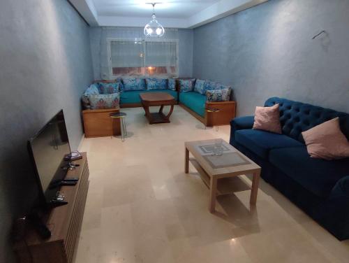 a living room with blue couches and a tv at Appartement Résidence fermée in Casablanca