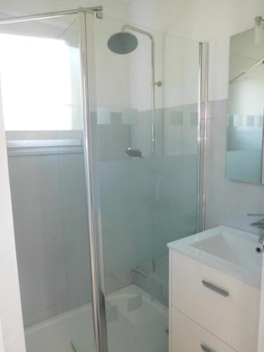 La salle de bains blanche est pourvue d'une douche et d'un lavabo. dans l'établissement LES BRUYERES, à Léon