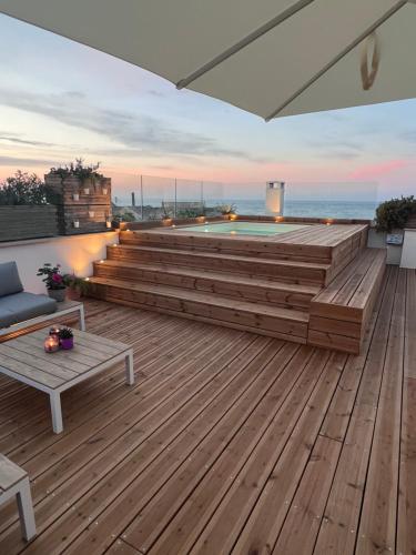a rooftop deck with a swimming pool and wooden stairs at Porta Vetere - Boutique Rooms in Trani
