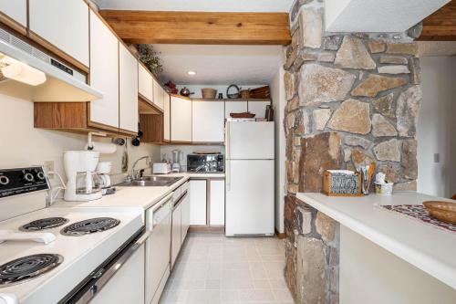 a kitchen with white appliances and a stone wall at Ski Harbor 14 in McHenry