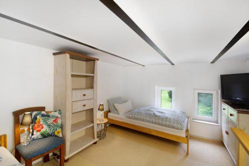 a bedroom with a bed and a tv and a chair at Tiny Appartment Xanten am See in Xanten