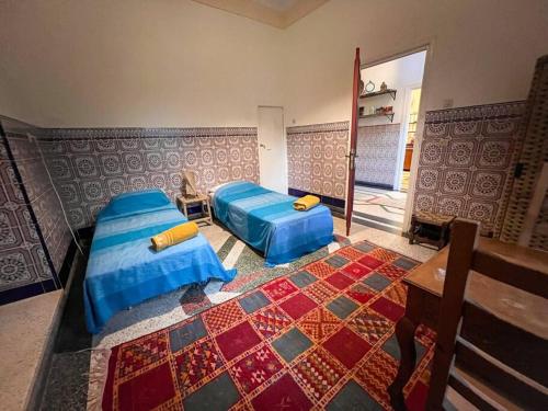 a bedroom with two beds and a rug at Historic Rue de la Kasbah Villa in Tangier