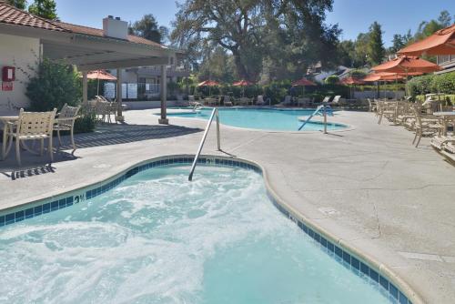 a swimming pool in a resort with tables and chairs at Riviera Oaks Resort in Ramona