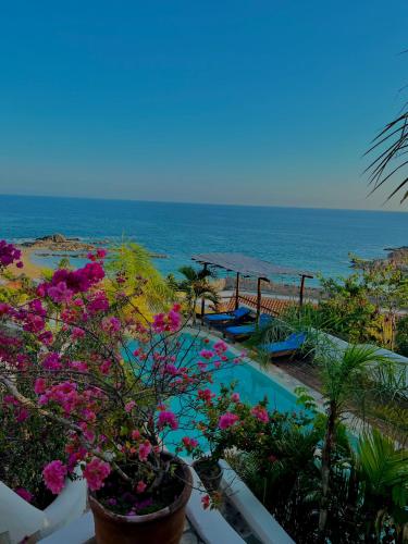 a view of the ocean from a balcony with flowers at Hotel Boutique casa la Malagueña in San Agustinillo