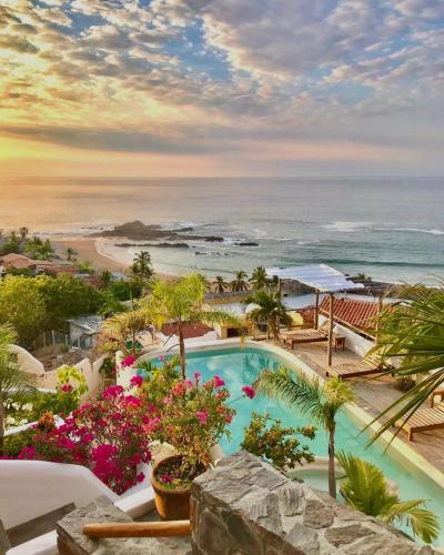 a resort with a swimming pool and the ocean at Hotel Boutique casa la Malagueña in San Agustinillo