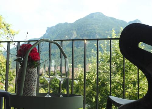 a table with two wine glasses and flowers on a balcony at Holzer 2.0 in Brannenburg