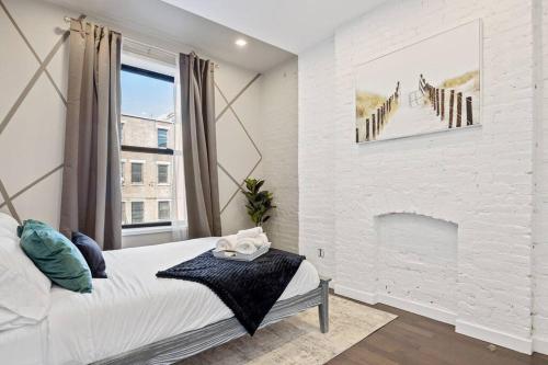 a bedroom with a white brick wall and a fireplace at SWJ 2nd - Times SQ, Brooklyn Bridge, LGA in 15 min in New York