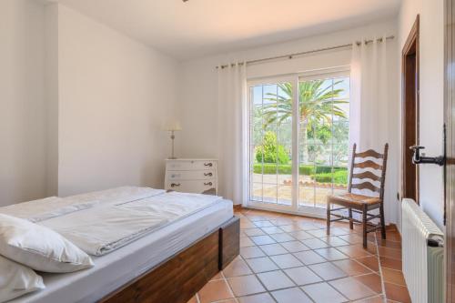 1 dormitorio con 1 cama, 1 silla y 1 ventana en Andalusische Luxus-Finca, en Arriate