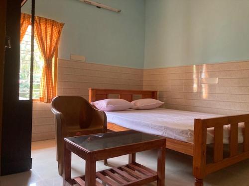 a bedroom with a bed and a chair and a table at DEN LODGE in Kulasegaram
