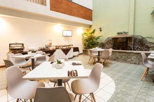 a restaurant with tables and chairs and a fireplace at Apartotel Tairona in San Pedro