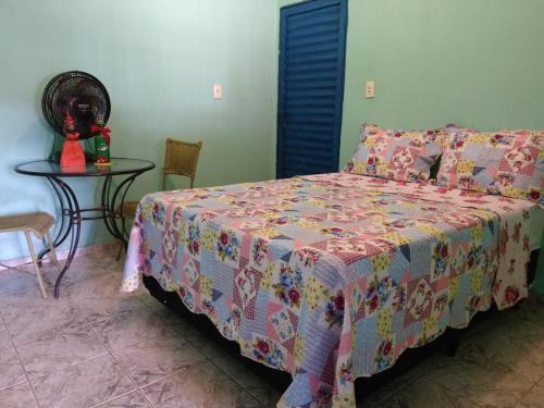 um quarto com uma cama e uma mesa com uma colcha em Pousada Joao & Maria em Pirenópolis