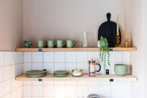 a kitchen shelf with plates and other items on it at Kim's City Escape in Cardiff