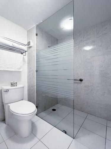 a bathroom with a toilet and a glass shower at Quinta Dorada Hotel & Suites in Saltillo