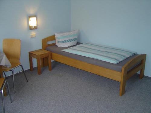 ein kleines Schlafzimmer mit einem Bett und einem Stuhl in der Unterkunft Hotel Garni Pension Ruth in Mutterstadt