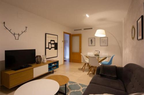 sala de estar con sofá, TV y mesa en Apartamento La Calma, en Lliber