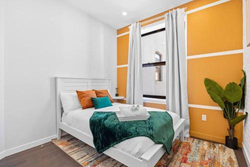 a bedroom with an orange and white bed and a window at SWJ 3rd - Sleeps 7,Close to LGA,Times Sq in 25 min in New York