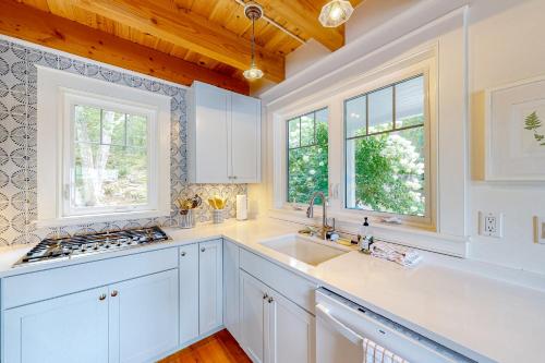 una cucina con armadi bianchi, lavandino e finestre di Periwinkle Cottage a Westport