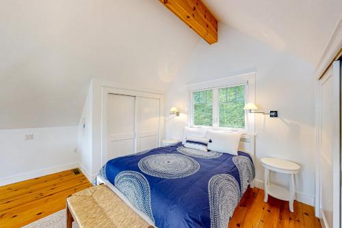 um quarto com uma cama azul num quarto com uma janela em Periwinkle Cottage em Westport