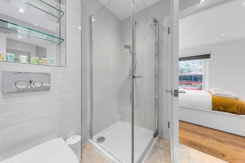 a glass shower in a bathroom with a bed at Flourish Apartments - The Annex - Dulwich Village in London