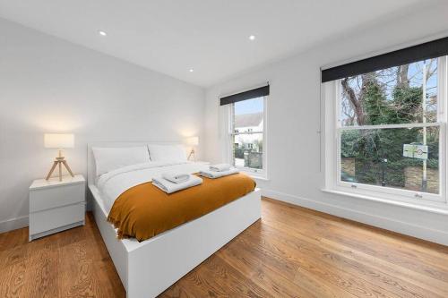 a white bedroom with a bed and two windows at Flourish Apartments - The Annex - Dulwich Village in London