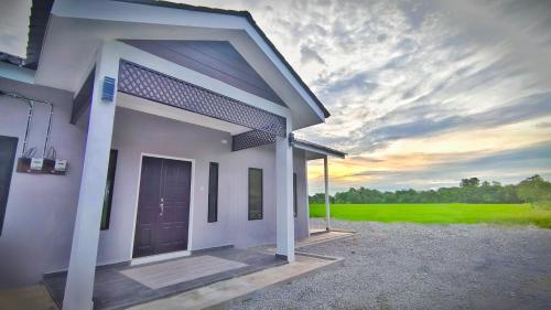 Paddy Villea Inn SPT Penang في Permatang Pauh: تقديم منزل مع غروب الشمس في الخلفية