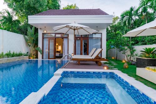 a villa with a swimming pool and a house at Riverside Hamlet Homestay & Villa in Hoi An