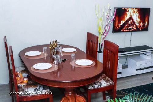 a dining room table with four chairs and a fireplace at Lapetals-Paradise-3bedrooms-ABNB machakos town in Machakos