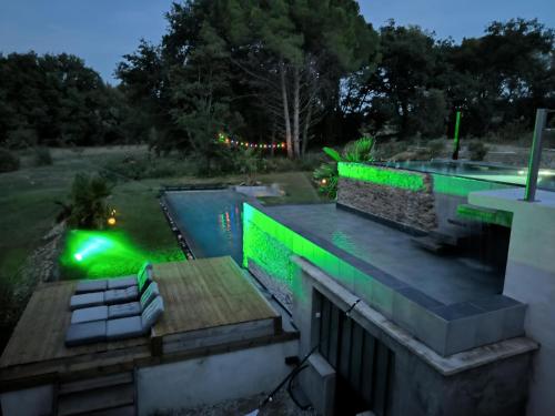 a house with a swimming pool with green lights at Mas L'Escale des Dentelles in Aubignan