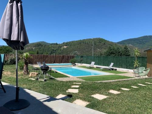 a backyard with a swimming pool and an umbrella at Villa La source & SPA in Pont-de-Labeaume