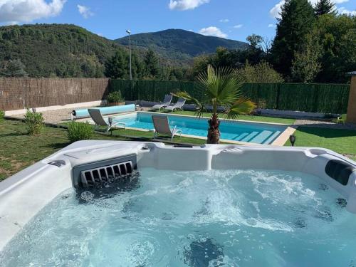a pool with a hot tub in a yard at Villa La source & SPA in Pont-de-Labeaume