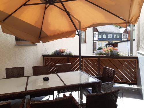 a table and chairs with an umbrella on a balcony at Hotel zur Post in Klingenthal