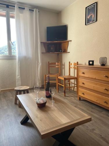 a living room with a wooden table with two wine glasses at Studio tout confort in Barcelonnette