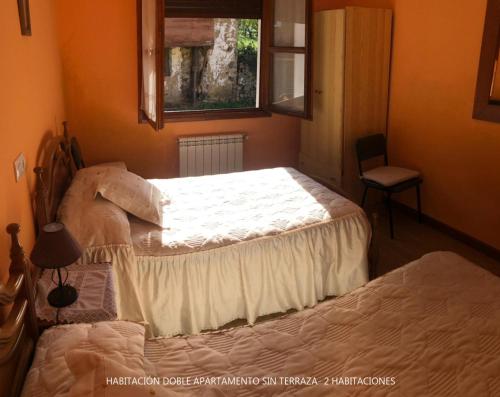 a bedroom with two beds and a window and a chair at Casa Valle in Cangas de Onís