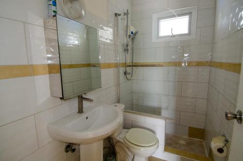 Un baño con lavabo, inodoro y ventana. en Tali & Tani Apartment, en Willemstad