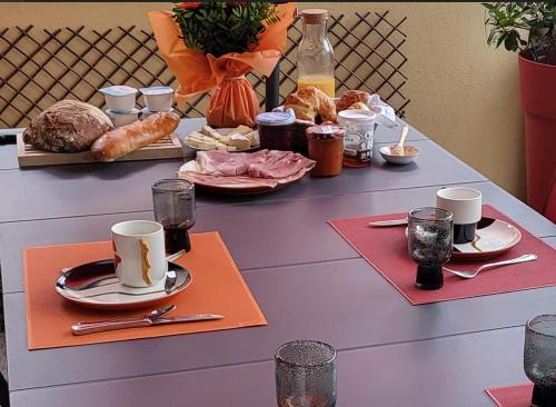 ein Tisch mit Tassen und Teller mit Essen drauf in der Unterkunft Poésie en partage in Giromagny