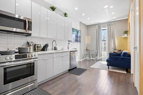 a kitchen with white cabinets and a blue couch at SWJ 5th - Perfect for Tourism: Near Train, Times Sq, Dining in New York