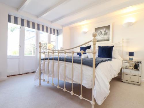 a bedroom with a white bed and a window at Potters Barn in Helston