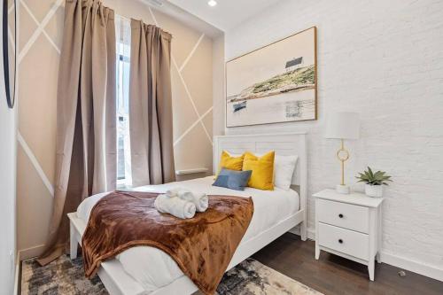 a bedroom with a white bed with yellow and blue pillows at SWJ 5th - Perfect for Tourism: Near Train, Times Sq, Dining in New York