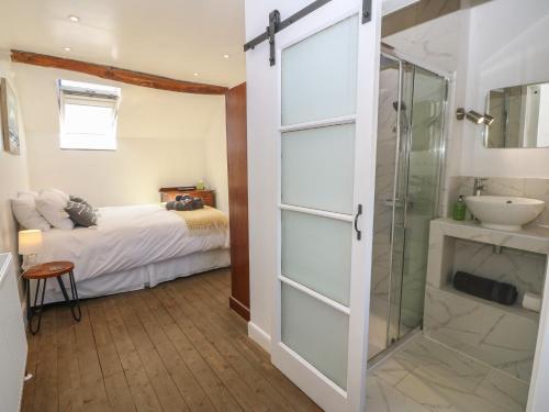 a bathroom with a shower and a sink and a bed at Yr Ysgubor in Dyffryn