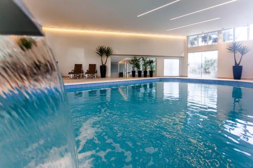 a large swimming pool with blue water in a building at Marambaia Hotel e Convenções in Balneário Camboriú