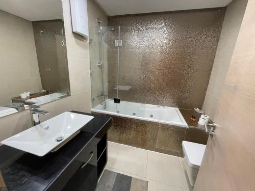 y baño con bañera, lavamanos y bañera. en Appart de Luxe front de mer Prestigia Plage des Nations, en Sale