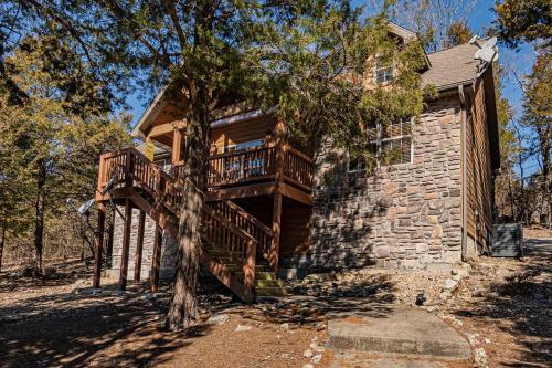 a log cabin with a deck on the side of a house at Local Hero Lodge in Reeds Spring