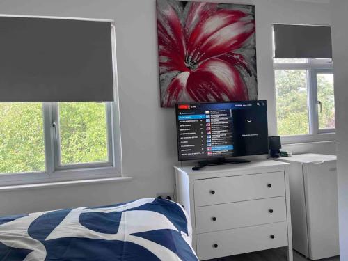 a bedroom with a bed and a computer on a dresser at Romford Cosy Studio Flat in Havering atte Bower