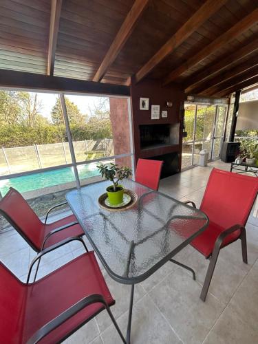 una mesa de cristal y sillas en una habitación con piscina en Nuestro hogar en Villa General Belgrano