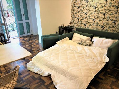 Cama en una sala de estar con sofá verde en Apto MILAO na Vila Paraíso, prático e relaxante en Maringá