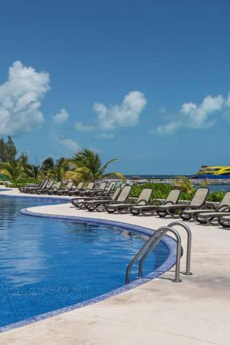 a swimming pool with lounge chairs and the ocean at Seacost Beachfront 2BDR with pool by Casa Paraiso in Cancún