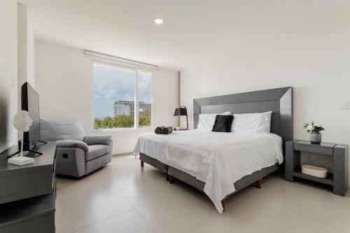 a bedroom with a bed and a chair and a window at Seacost Beachfront 2BDR with pool by Casa Paraiso in Cancún
